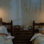 A grandfather and grandson sharing stories in their cozy bedroom at night.